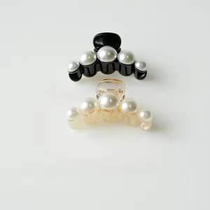 Detail of elegant black and champagne pearl hair claws with a gradient pearl finish