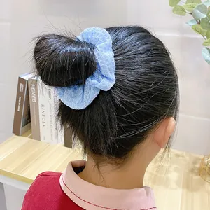 Light blue oversized knit scrunchie with mesh texture worn on a bun hairstyle