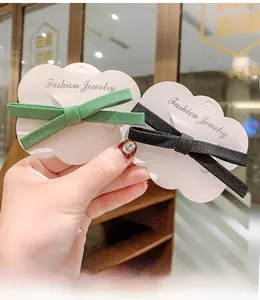 Detailed close-up of ribbon bow hair clips in black and dark green fabric texture