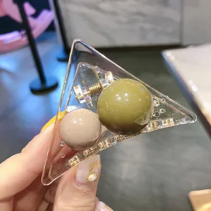 Detail of transparent acrylic triangle hair claw clip with green and beige round beads