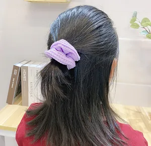 Detailed view of a purple knitted waffle texture scrunchie worn on a ponytail