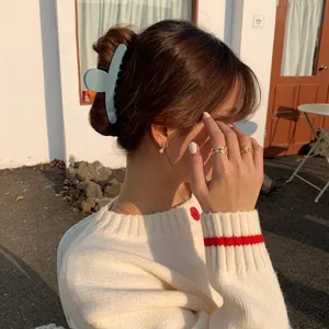 Pince à cheveux mate bleu clair portée par un mannequin sous une lumière naturelle chaude