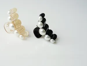 Detail of elegant black and beige hair claws with curved white imitation pearls