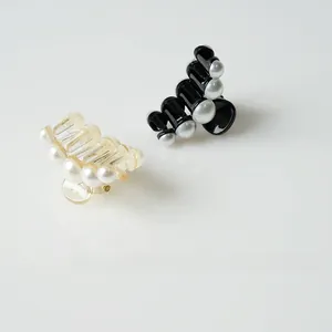 Detail of elegant black and cream hair claws with artificial pearl embellishments