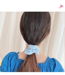 Detail of a light blue knitted scrunchie showing soft fabric texture on a ponytail