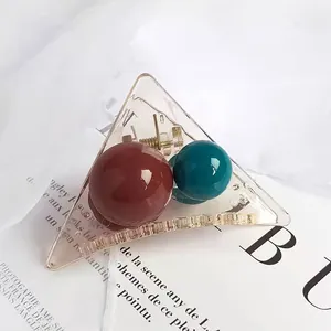 Detail view of transparent triangle hair claw with burgundy and dark green beads