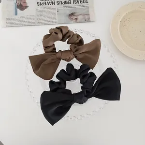 Detailed macro view of brown and black satin bow scrunchies on an elegant glass tray