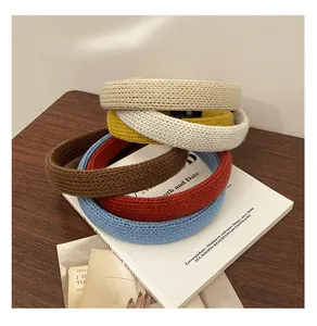 Gros plan de serre-têtes en maille épaisse beige jaune marron rouge et bleu sur bois