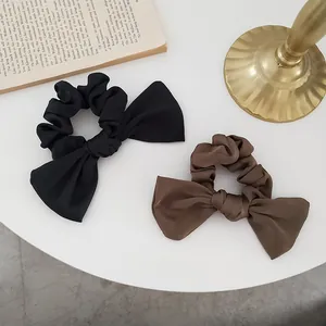 Detail of satin bow scrunchies in black and brown on an elegant vintage background