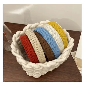Gros plan de six serre-têtes en tricot épais de couleurs variées dans un panier