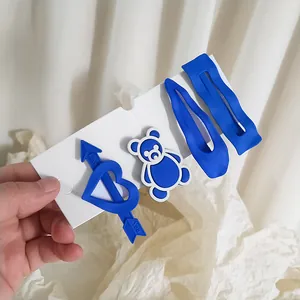 Détail du set de barrettes bleu Klein mat comprenant formes de cœur, ours et goutte
