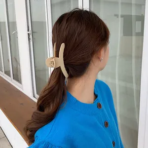 Grande pince à cheveux mate beige fixant un chignon sur de longs cheveux bruns