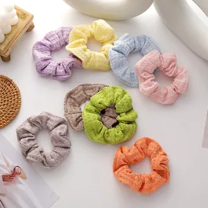Detail of waffle knit fabric scrunchies in various pastel colors on a cozy tabletop