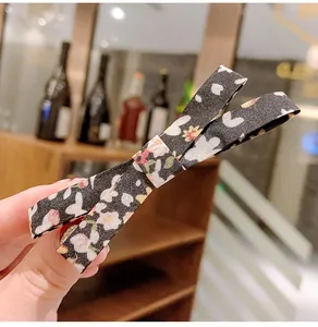 Detail of black fabric bow hair clip featuring rabbit and floral patterns on metal clip