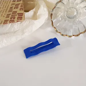 Gros plan de la pince à cheveux bleu Klein mat avec design ondulé sur papier