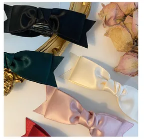 Detail of satin bow hair clips in multiple colors with elegant vintage rose background