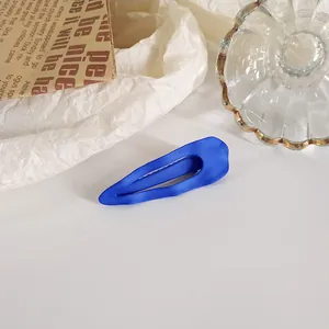Gros plan sur une pince à cheveux bleu mat sur un fond de papier texturé blanc