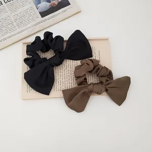 Detailed view of black and coffee satin bow scrunchies on a book for a French style