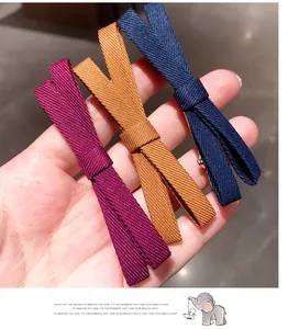 Detailed texture of colorful ribbed fabric bow hair clips in purple, yellow and blue