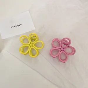 Close-up of matte pink and yellow hollow flower hair claws on white crepe paper