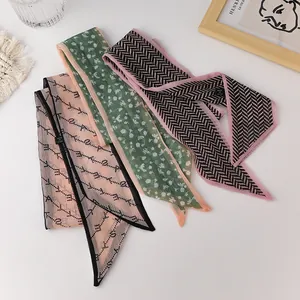 Detailed view of three chiffon twilly scarves with floral and letter patterns