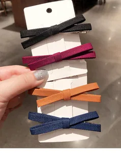 Set of four fabric bow hair clips in navy, red, yellow, and black on a display card