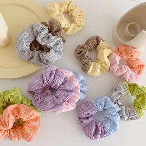 Assorted waffle knit scrunchies in pastel colors on a white minimalist tabletop