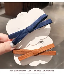 Close-up of navy blue and orange ribbon bow hair clips on a cloud display card