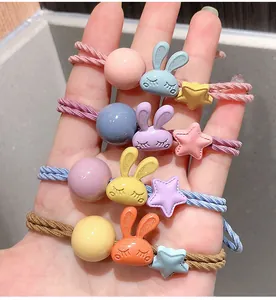Détail de quatre élastiques à cheveux colorés avec breloques lapin, étoile et perle