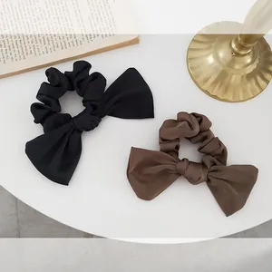 Elegant satin bow scrunchies in black and brown colors shown in a vintage lifestyle setting
