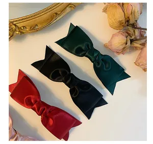 Detailed macro of French style satin bow hair clips in green black and wine red colors