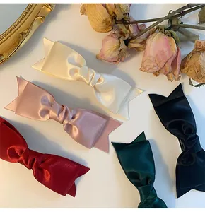Flat lay of multiple elegant satin bow hair clips in various colors with vintage props