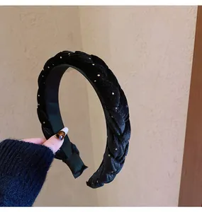 Detailed view of black braided velvet headband featuring small golden decorative studs