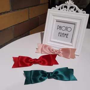 Detailed view of pink, red, and green satin bow hair clips with silky texture