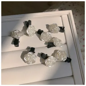 Détail macro de huit pinces à cheveux rose blanc crème avec éclat perlé sur plateau