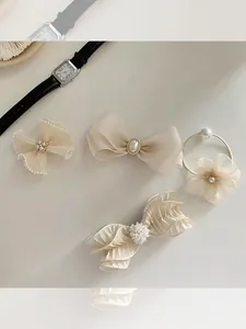 Detail of four-piece beige hair accessory set with organza bows and pearl decorations