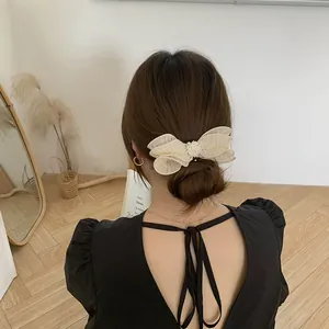 Detail of cream tulle bow hair clip with pearls worn on elegant updo hairstyle