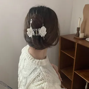Elegant white floral hair claw clip accessory styled on a wavy brunette hairstyle