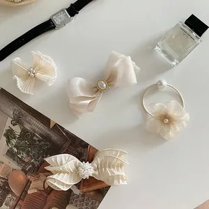 Detail of cream bow hair clips and pearl hair ties set on an elegant tabletop