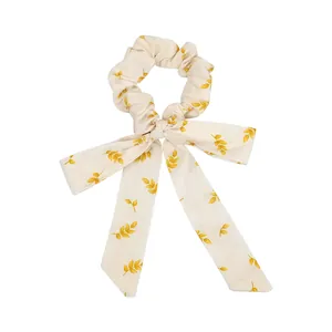 Eleganter elfenbeinfarbener Scrunchie mit gelbem Blattmuster und langen Bändern auf weiß