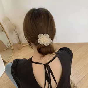 Close-up of elegant cream tulle flower hair clip with pearl detail worn on hair