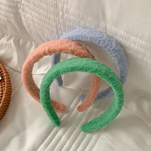 Detailed texture of ruffled candy-colored sponge headbands in blue, pink, and mint green
