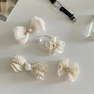 Detail of 4-piece cream ribbon hair clips and ties with faux pearls and rhinestones