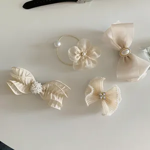 Detail of four-piece cream hair accessory set with bows, pearls, and chiffon textures