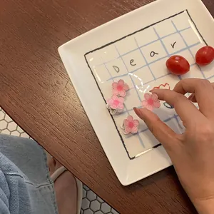 Set aus rosa Kamelien-Haarspangen auf einem dekorativen weißen Keramikteller im Set