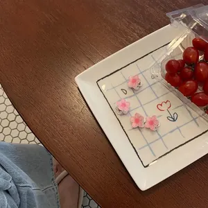 Set mit vier süßen rosa Kamelien-Kirschblüten-Haarspangen auf einem weißen Keramikteller