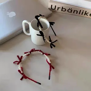 Retro velvet bow pearl headbands in black and burgundy displayed on a modern desk