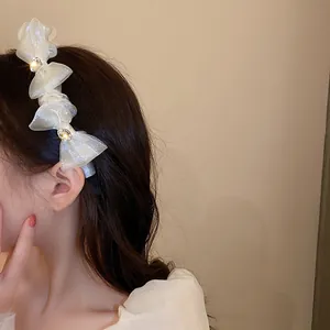 Detail of white organza headband with layered bow design and crystal accents on model