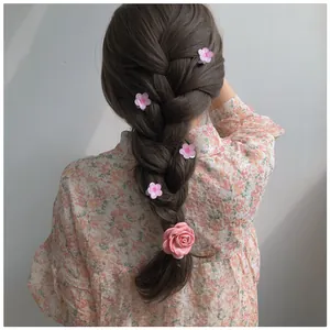 Pink camellia and rose hair clips styled on a brunette braid for a sweet look