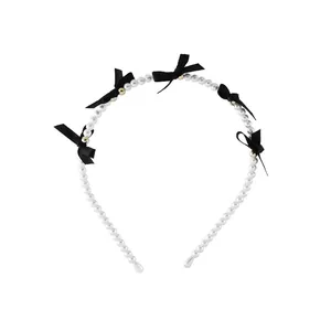 Elegant beaded headband with white pearls, black satin bows and golden accents on white background